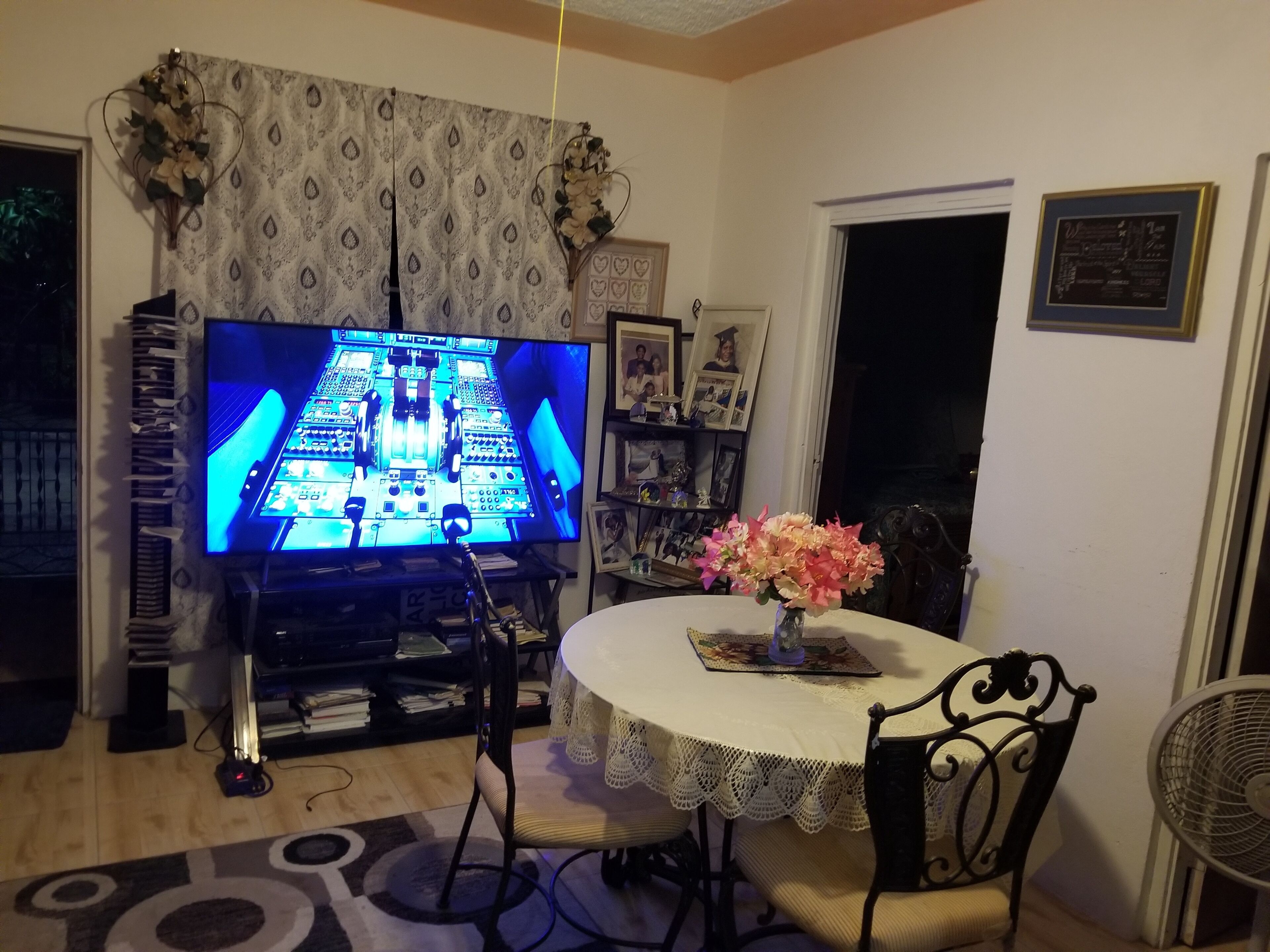 A living room with a television, a table with a lace tablecloth, and a chair.