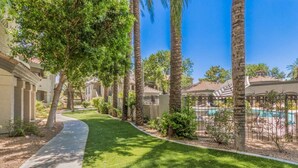 A residential area with a well-maintained lawn, palm trees, and a swimming pool.