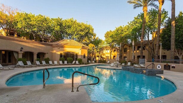A swimming pool with lounge chairs and palm trees.
