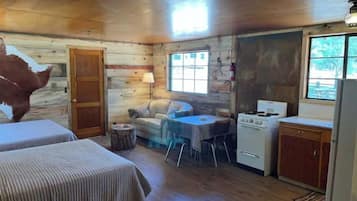 A cabin with two beds, a dining table, a stove, and a refrigerator.