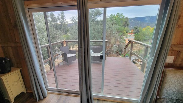 Quarto com uma grande porta de vidro deslizante que dá para um terraço ao ar livre com uma cadeira e mesa.