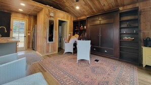 Um quarto amplo com teto de madeira, um grande ventilador de teto e um tapete estampado.