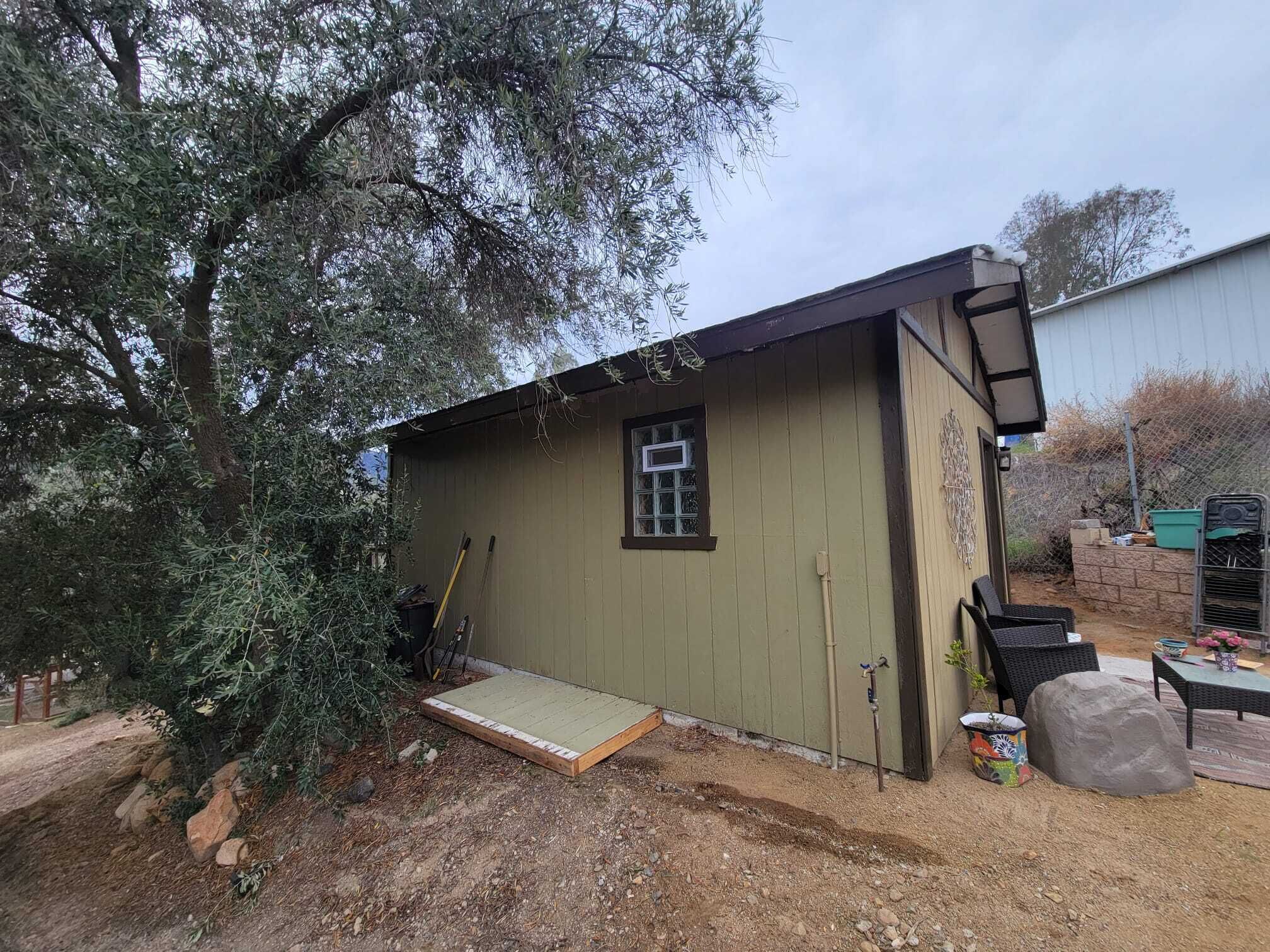 A small, single-story building with a green exterior and a small window.