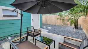 An outdoor patio area with a black umbrella, two chairs, and a small table.