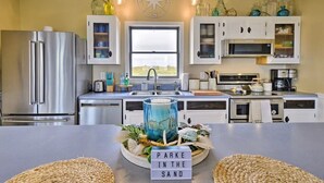 Una cucina moderna con elettrodomestici in acciaio inossidabile, mobili bianchi e un'isola centrale con un elemento decorativo.