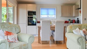 A modern kitchen with built-in appliances, a dining area with a table and chairs, and a cozy seating area with two sofas. - Canadian timber lodge with direct views to the Alpacas. (Rowrah, near Cockermouth)