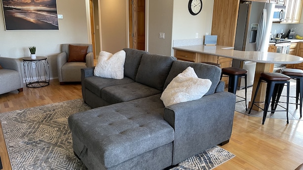 A modern living room with a sectional sofa, a small side table, and a patterned rug.