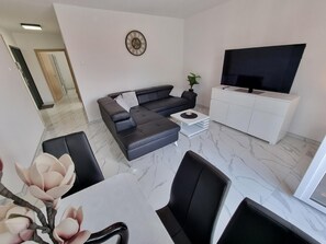Relax in this stylish living room with a comfortable sofa, flat-screen TV, and dining area.