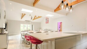 Eine moderne Küche mit einer großen Kochinsel, Barhocker und Holzbalken an der Decke.