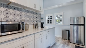 Una cocina moderna con armarios blancos, un refrigerador de acero inoxidable y un microondas.