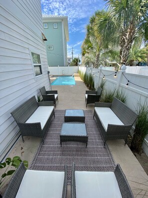 Un jardin avec une piscine, des meubles en osier et un tapis Ă motifs.