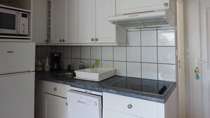 Una cucina compatta con mobili bianchi, un forno a microonde, una lavastoviglie e un piano cottura a gas.