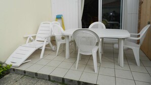 Un patio con un tavolo e sedie bianche, una piccola sedia bianca e un tubo giallo.