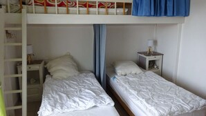 Un letto a castello con due letti singoli in basso, ciascuno con un cuscino e un comodino con una lampada.