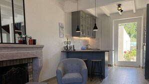 Een moderne woonkamer met een open haard, een zithoek en een keuken met barstoelen.