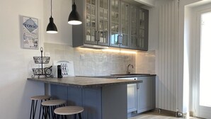 Een moderne keuken met een centraal eiland, barstoelen, hanglampen en een spatwand met een 'Tonic' bord.