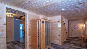 A wooden interior with a central glass door, a staircase, and a door with a circular decoration. - The Winsor Lodge | Saco River Group Retreat with Bar, Arcade, Hot Tub & Sauna (Conway)