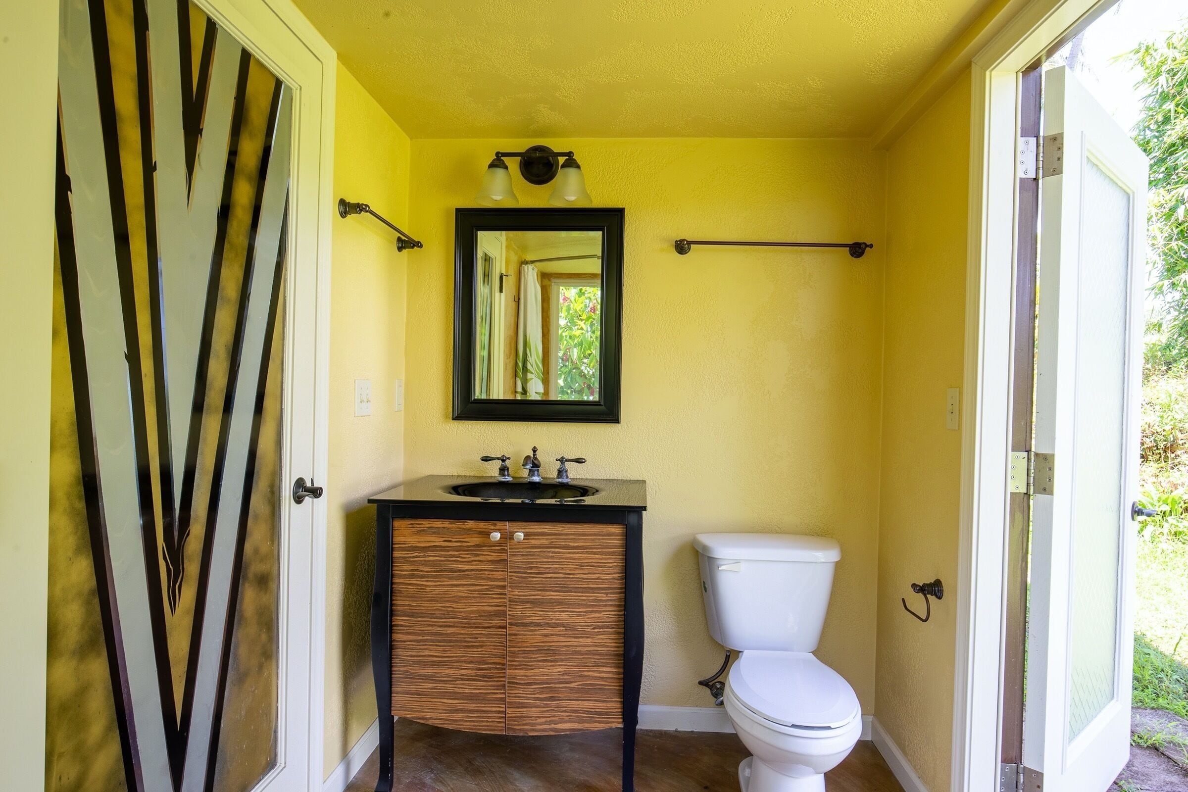 A bathroom with a wooden vanity, a white toilet, and a mirror above the sink.