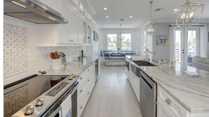A modern kitchen with white cabinetry, a central island, and a view to the outside. - New Waterfront 3BR townhouse with boat dock and  private heated pool!  (Stuart)