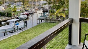 A balcony with a view of a marina, boats docked, and palm trees. - New Waterfront 3BR townhouse with boat dock and  private heated pool!  (Stuart)