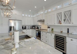 A spacious kitchen with white cabinetry, a marble countertop, and a stainless steel refrigerator. - New Waterfront 3BR townhouse with boat dock and  private heated pool!  (Stuart)
