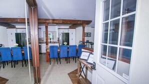 Un espace repas avec des chaises bleues, un banc en bois et un panneau d’accueil.