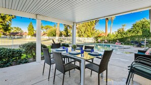 Eine überdachte Terrasse im Freien mit Pool, Esstisch, Stühlen und Blick auf die Umgebung.