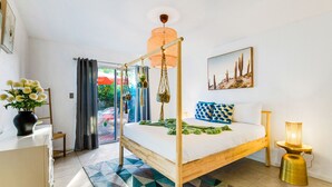 Ein Schlafzimmer mit Himmelbett, einer hängenden Pflanze, einem gemusterten Teppich und einem Bild an der Wand.