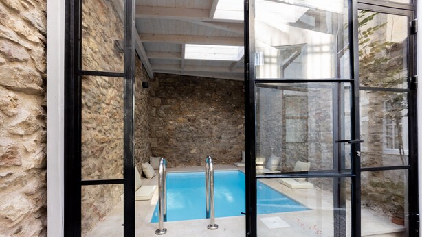 A stone-walled room with a glass door leading to a pool area. - Incomparable Plaka's Lux 2bdrm Apt w/Pvt Heated Pool (Athens)