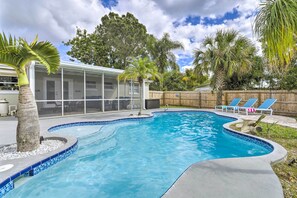 A swimming pool with a curved edge, surrounded by a wooden fence and palm trees. - Merritt Island Oasis w/ Pool ~ 7 Mi to Beach! (Merritt Island)