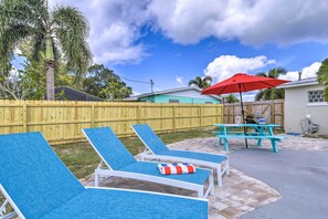 A backyard with blue lounge chairs, a red umbrella, and a picnic table. - Merritt Island Oasis w/ Pool ~ 7 Mi to Beach! (Merritt Island)