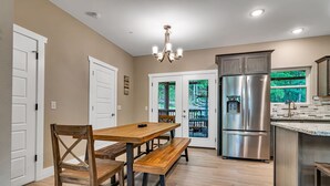 Una cocina moderna con comedor, electrodomésticos de acero inoxidable y vistas a través de la puerta de vidrio.