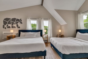 A hotel room with two beds, a large window with curtains, a wall-mounted animal decal, and bedside lamps.