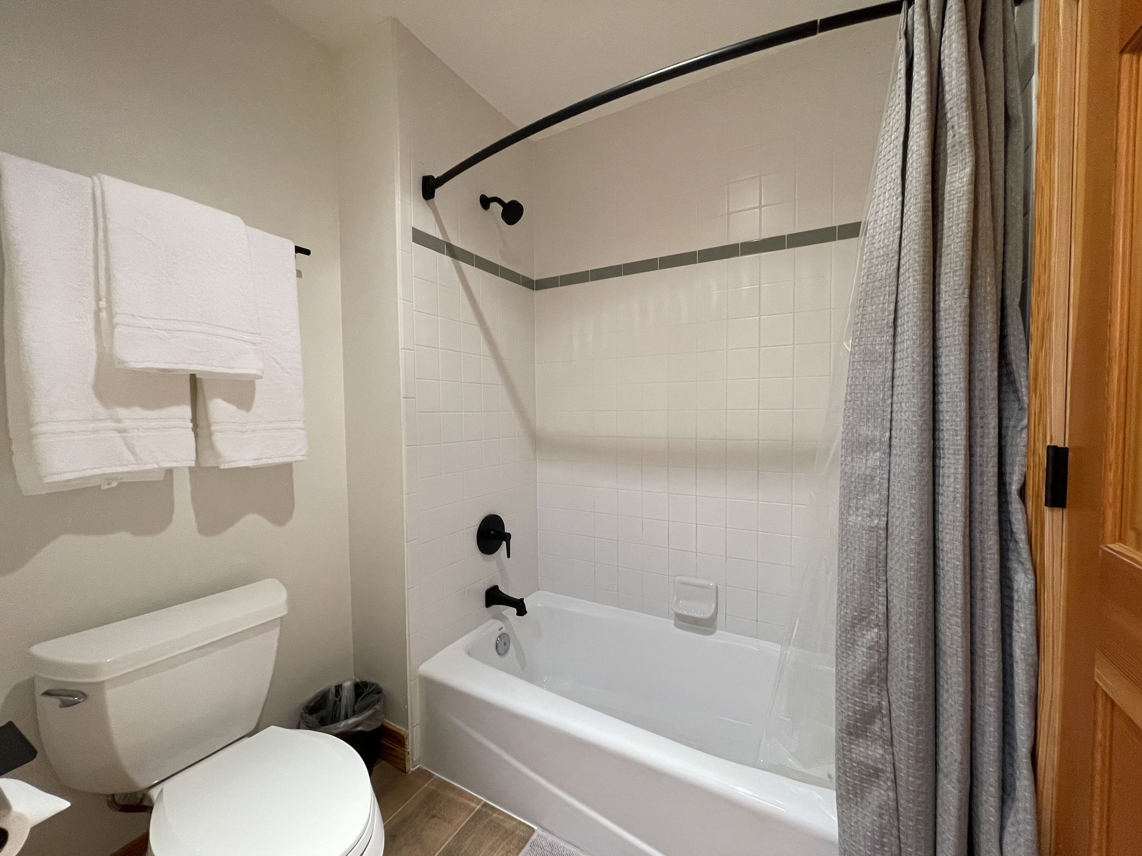 A bathroom with a white bathtub, a toilet, and a shower curtain.