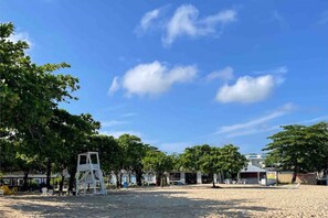 A beach area with trees, a lifeguard stand, and a small building.
