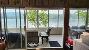 Habitación con puerta de vidrio corrediza que da a una vista del lago, mobiliario de mimbre y una pequeña mesa.
