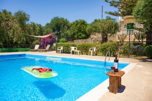 A swimming pool with lounge chairs and a bottle of wine on a wooden stand. - Fran Apartment: Cozzy apartment with a shared pool, breakfast options and close to the beach (Saint Spyridon)