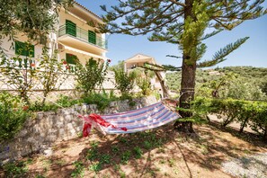 A building with a balcony, a hammock, and a tree. - Fran Apartment: Cozzy apartment with a shared pool, breakfast options and close to the beach (Saint Spyridon)