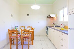 A small kitchen with a dining table and chairs, a sink, and a window.