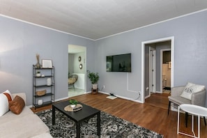 A living room with a sofa, a coffee table, a TV, and a bookshelf.