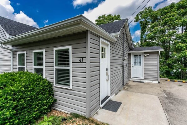 A single-story house with a grey siding exterior, a front door, and a small porch area.