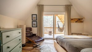 Une chambre avec un lit en mezzanine, un bureau, une chaise et un hamac suspendu.
