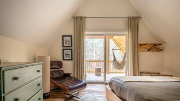 A bedroom with a loft bed, a desk, a chair, and a hanging hammock.