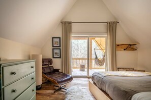 Un dormitorio con cama alta, escritorio, silla y una hamaca colgante.