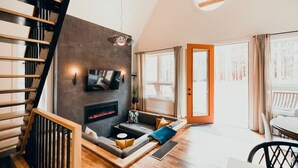 Un salon moderne avec une cheminée, un escalier et un coin repas.
