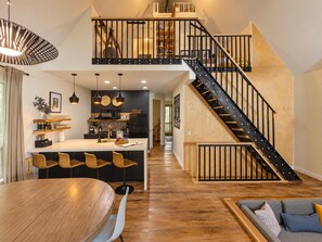 Une cuisine moderne dotée d’un îlot central, de planchers en bois et d’un escalier avec des rampes noires.
