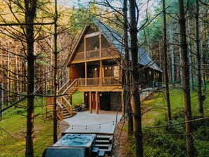 Un chalet à deux étages doté d’un balcon, entouré d’arbres.