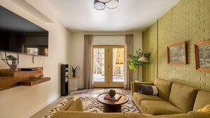 Un salon avec un canapé, une table basse et un téléviseur fixé au mur.