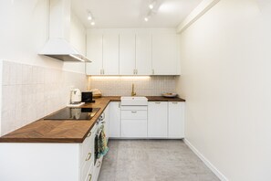 A compact kitchen with white cabinets, a wooden countertop, and a built-in oven.