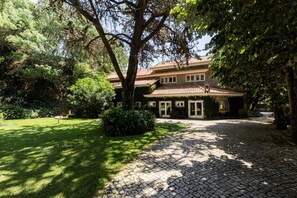 A two-story house with a tiled roof, surrounded by a well-maintained garden and a cobblestone driveway. - A Hideaway Paradise by CadenzaLux (Cascais)